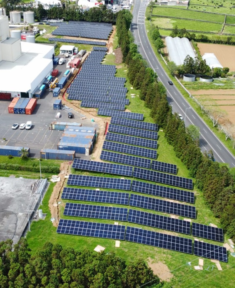 Large-scale photovoltaic solar panel installation with blue panels arranged in rows under bright sunlight